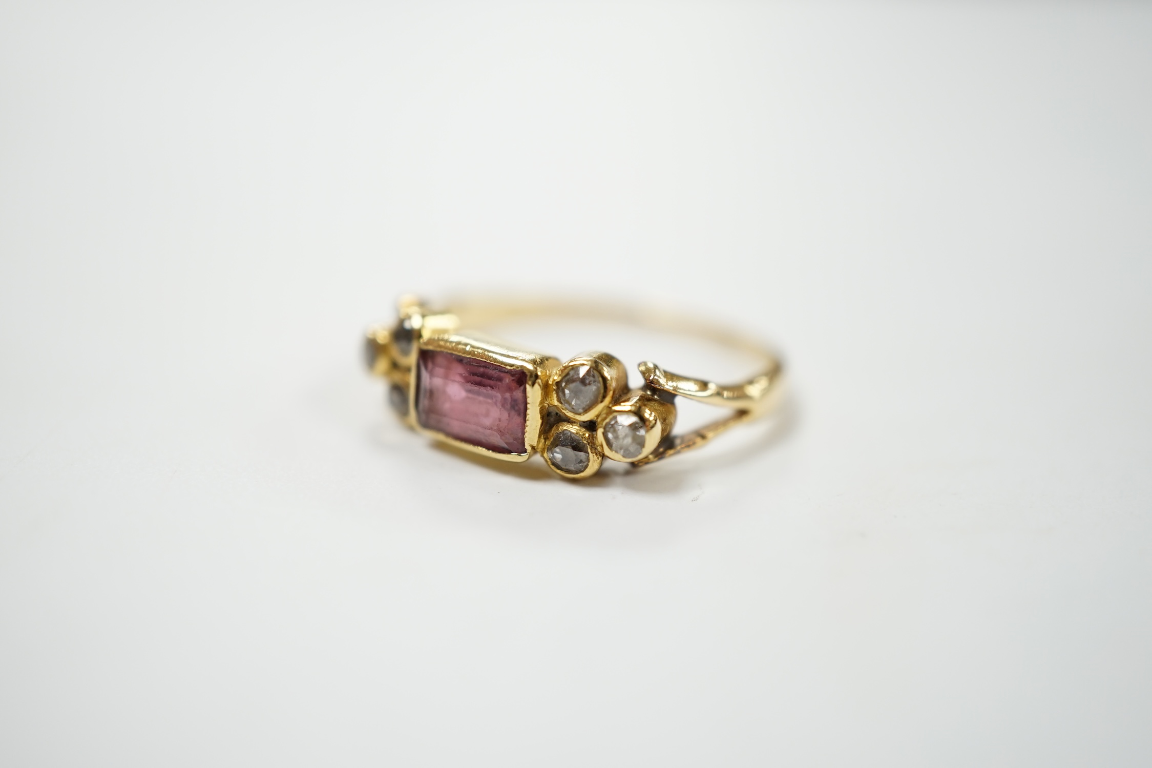 A yellow metal and single stone rectangular cut garnet? set ring, with six stone diamond set shoulders, size L, gross weight 2.5 grams. Condition - poor to fair